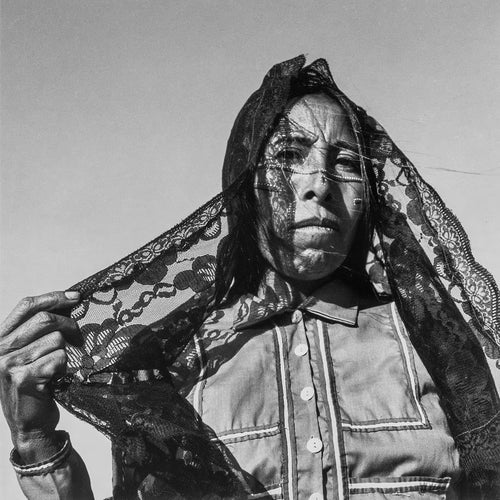 Person wearing a lace headscarf against a plain background