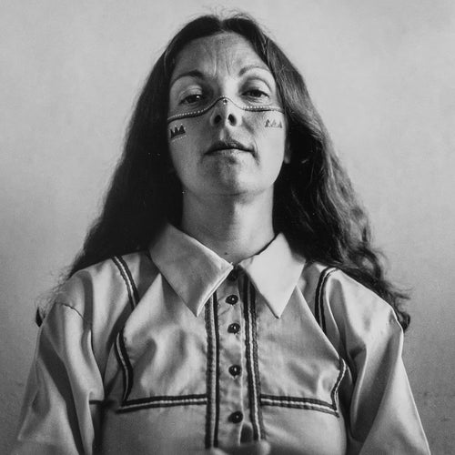 Black and white photo of a person with traditional face paint wearing a patterned shirt.