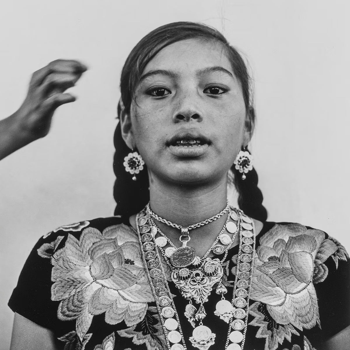 Black and white portrait of a person wearing traditional jewelry and clothing.